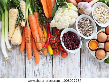 Healthy eating concept ingredients. Seasonal vegetables, quinoa,red beans,oatmeal, eggs and fresh herbs over old wooden table. Overhead view