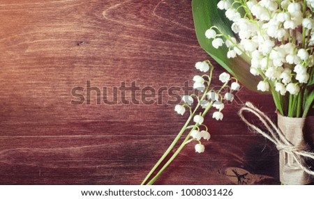 Bouquet of young lilies of the valley on a wooden table