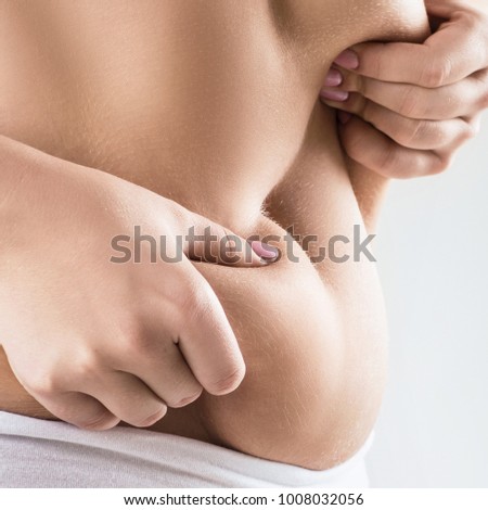 Woman in white underwear holds belly fat.