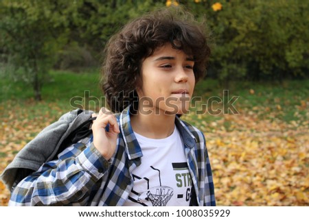 An outdoor portrait of a handsome curly boy in a park