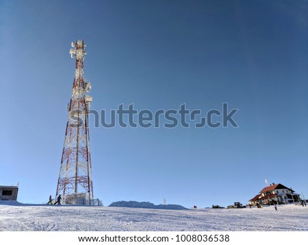 Telecommunication tower with dish and mobile antenna against blue sky in the mountains during winter season in Romania. Telecommunication tower with satellite dish in winter background