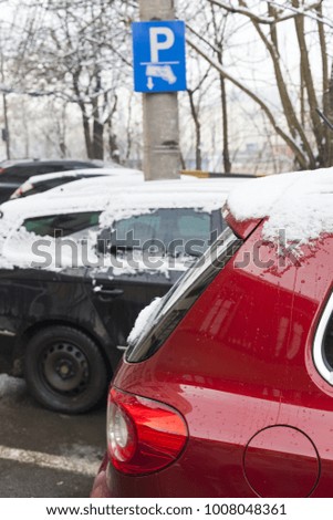 Picture of cars at a parking space & blue parking sign in the city on a winter day