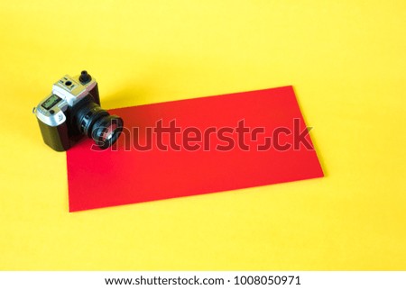 Mini camera toy and red envelop on yellow background with copy space for add text.
