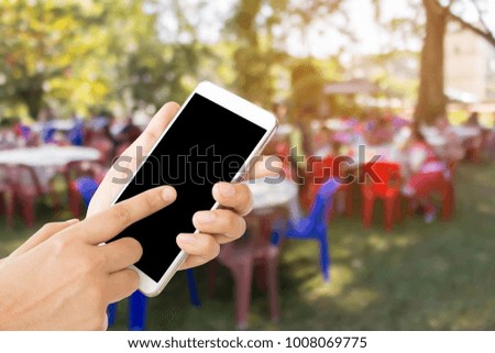 woman use mobile phone and blurred image of people in the outdoor party 