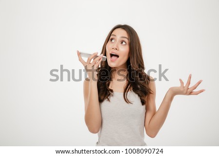 Portrait of pretty woman with long brown hair emotionally speaking on cellphone having pleasant mobile dialog isolated over white background
