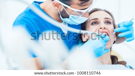 Beautiful young woman looking up relaxed during a painless dental procedure done by her reliable dentist in a modern clinic with sterile equipment Royalty-Free Stock Photo #1008110746