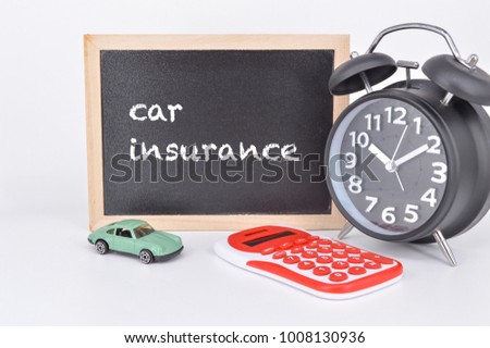 Miniature car, alarm clock, calculator and blackboard written word CAR INSURANCE on white background. Conceptual image. Selective focus.