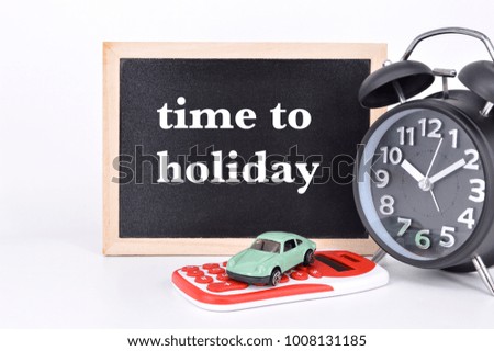 TIME TO HOLIDAY written on blackboard with miniature car, calculator and alarm clock on white background. Concept image.