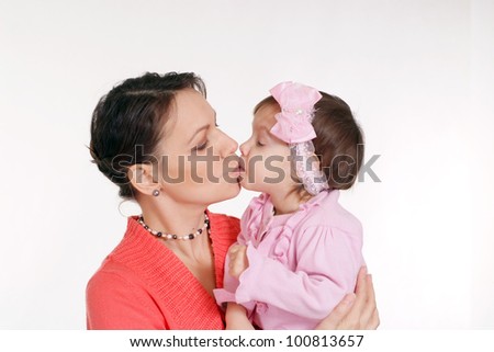 Mother kisses her little daughter on a white background