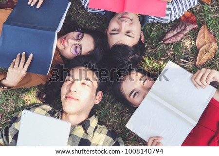 Students read a book lying on the grass.