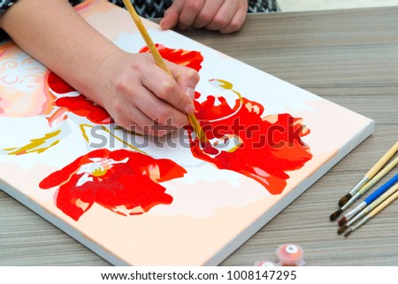 Woman draws a painting with a brush and paints