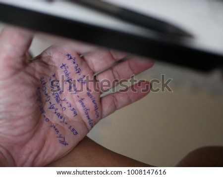A hand with mathematical formulas written on it sneakily opened under the table to cheat an examination Royalty-Free Stock Photo #1008147616