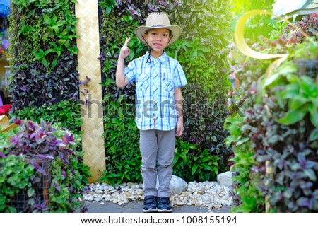 curt Asian boy wearing shirt and cowboy hat  smiling in forest