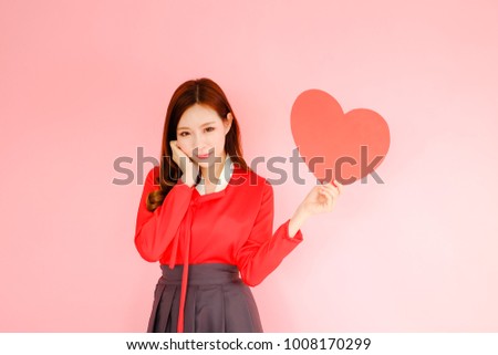 Portrait beautiful asian woman wearing red hanbok dress on pink background, korea style, valentine day in love concept, model is holding red heart sign in hand