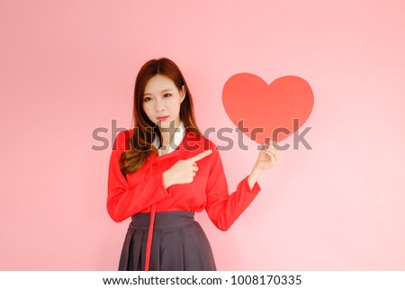 Portrait beautiful asian woman wearing red hanbok dress on pink background, korea style, valentine day in love concept, model is holding red heart sign in hand