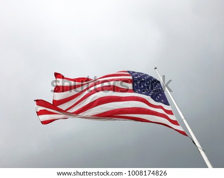 American flag on the background of a gloomy gray sky. Flag of the USA