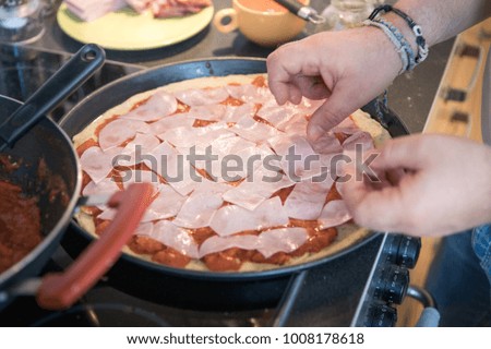 Preparation of authentic homemade pizza with ham in home kitchen