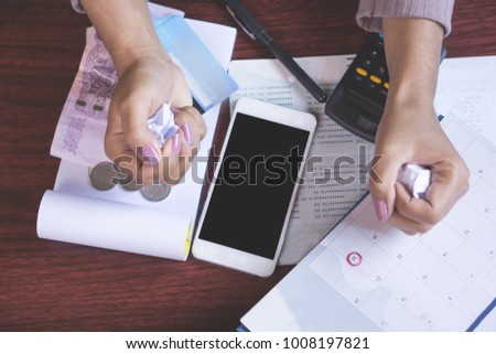 deadline calendar, smart phone,money,credit card,calculator and saving account on table with blur background of angry business woman hand crumpling paper, debt,payment concept 