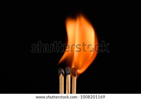 Three matches and burn bright on a black background closeup