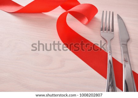 Menu background for restaurant with silver cutlery and red ribbon on wood table background. Elevated view
