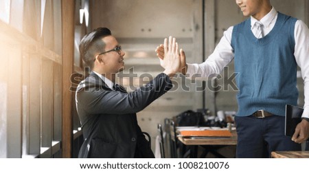 Business people giving five to their colleague after dealing with foreign partners and signing contract or agreement between companies