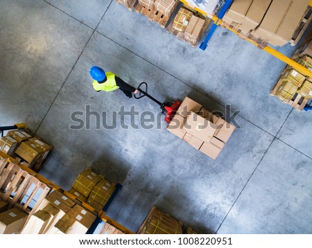 Male warehouse worker pulling a pallet truck. Royalty-Free Stock Photo #1008220951