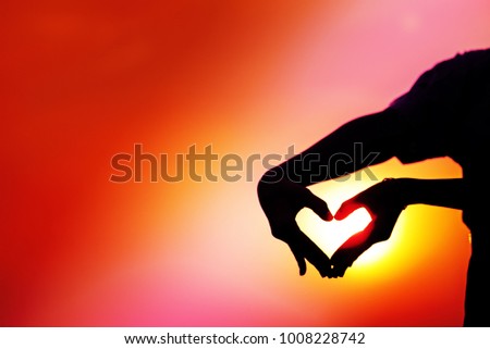 Silhouette of two hands make "heart symbol" with multi-color construction work  sunlight background,Love and Valentines concept,vivid color