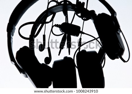 close up and silhouette a headphones with striped wires on a white gradient background
