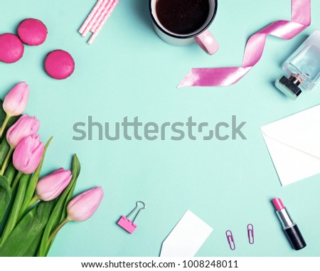 Pink tulips, coffee, macarons and other cute small objects on the mint color background