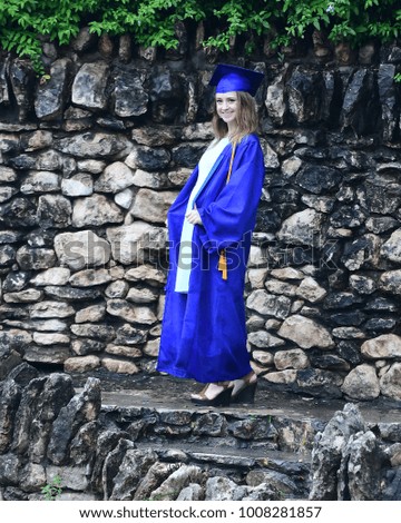 Teen girl in high school graduation gown posing for pictures in a beautiful botanical garden
