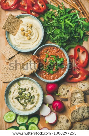 Vegan snack board. Flat-lay of various Vegetarian dips hummus, babaganush and muhammara with crackers, bread and fresh vegetables, top view. Clean eating, healthy, dieting food concept. Royalty-Free Stock Photo #1008297253