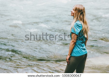 Young woman walking at river alone Lifestyle travel concept wild nature