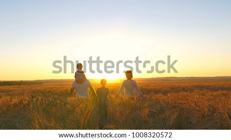 Happy family father mom and two sons walking in a wheat field and watching the sunset - 3
