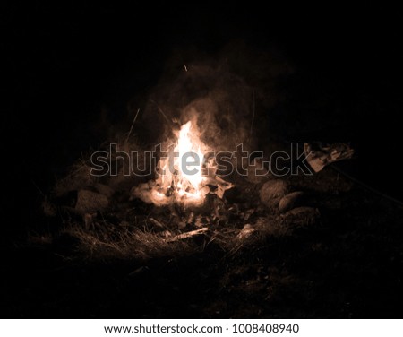 Bonfire lighting up the fireplace in the night, with red glowing wood and yellow flames