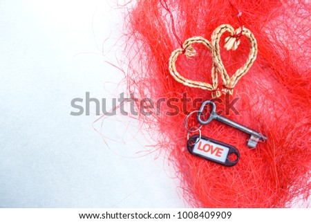 Flat lay hearts made of woven of willow twigs and steel key blank with orange Love text sign . Concept of path to heart. Valentines Day , 14 February. Red texture fibres Background , copy paste space.