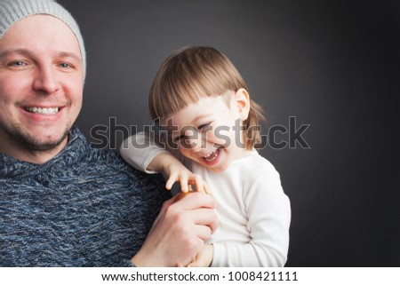 Dad plays with a lovely little son, sitting on his hands on a black background in the Studio. It amuses it with Apple and they both laugh. Photos to celebrate father's day.