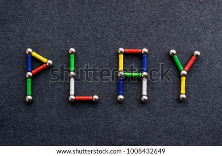 The word PLAY of colored sticks and balls, multicolor elements of the magnetic constructor. Children's sensory games, activity, creativity concept 
