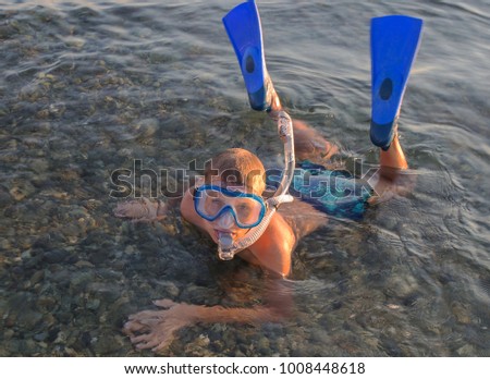 A teenager wearing a mask with tube   for diving and flippers background of the sea.