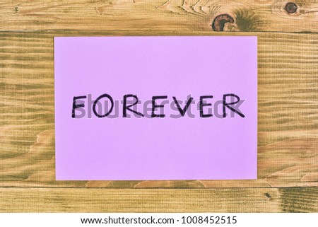 Paper with word forever on wooden table.Image is intentionally toned.