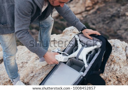 Urban adventurer or explorer, stock photographer unpacks backpack with photography equipment and drone. Ready to shoot aerial footage for sale or social media