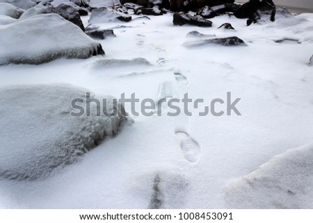 human footprints in the snow among rocks