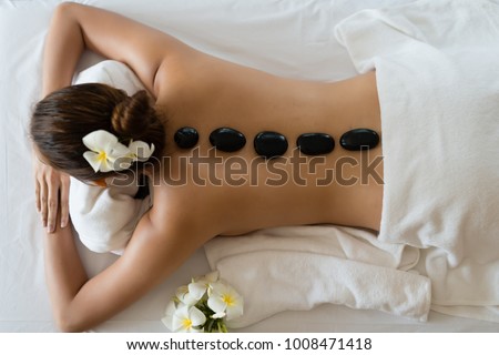 Young beautiful Asian woman relaxing in the Spa Stone Massage. Spa Hot Stones Royalty-Free Stock Photo #1008471418