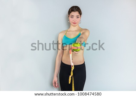 Beautiful young healthy woman. Diet image of a young athletic woman with measuring tape and green apple.