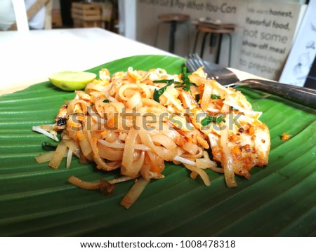 A famous food from Thailand called Pad-Thai, a fried noodle with shrimp and bean sprouts on a banana leaf serve with a piece of lemon on side dish.