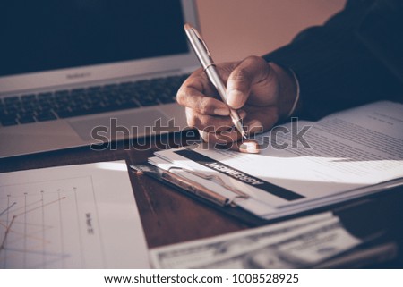 Businessman writing signed agreements on official documents to the company's profits. Which is filled with documents and concepts for the cooperation of its partners. 