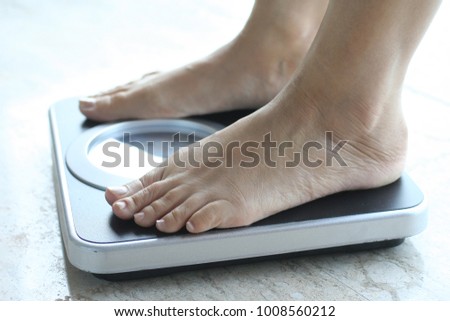 Lose weight concept, woman standing on scale measuring Royalty-Free Stock Photo #1008560212