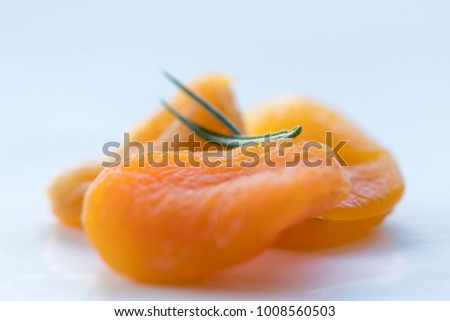 Picture composed by dried apricots and rosemaries. High-angle shot. Seen from above. Close-up.