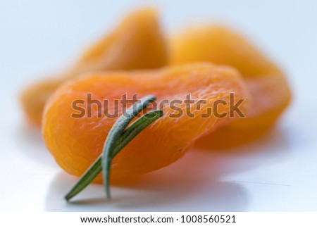 Picture composed by dried apricots and rosemaries. High-angle shot. Seen from above. Close-up.