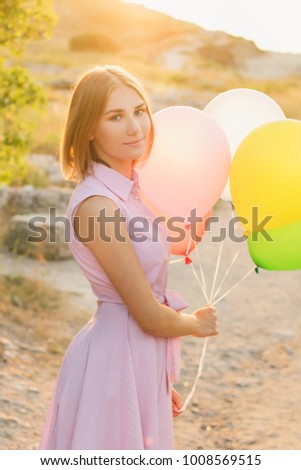 Happy girl posing with colorful air balloons. Soft toned photo.