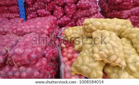 Onions and potatoes in stored in netting for distribution to market. Royalty-Free Stock Photo #1008584014